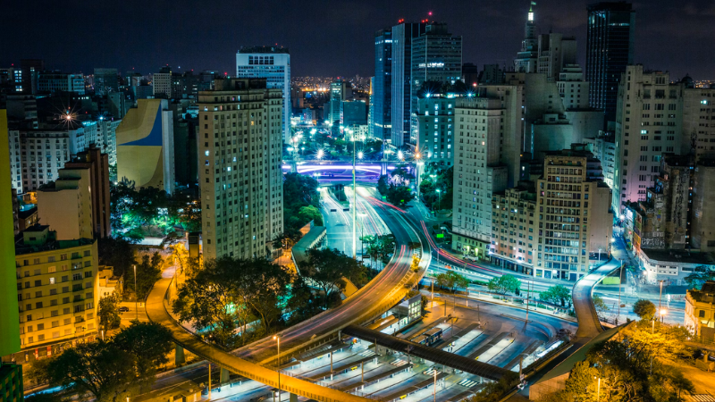 O que fazer em São Paulo: Avenida iluminada com ônibus e carros passando à noite em São Paulo, SP.