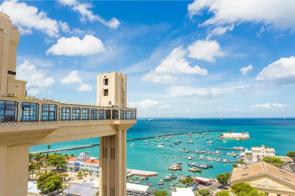 Vista para o Elevador Lacerda em Salvador, Bahia, em um dia ensolarado com mar e céu azul.